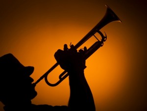 backlight musician playing trumpet on orange background